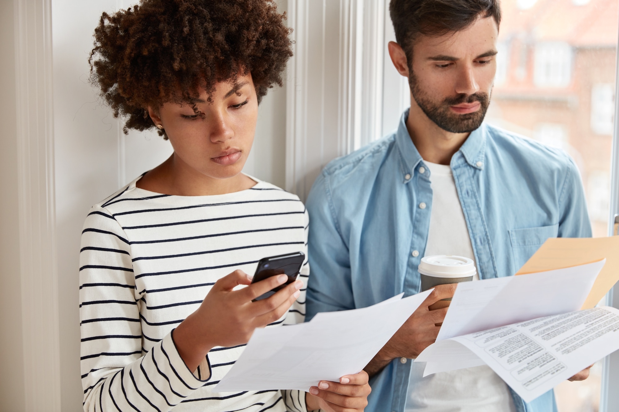 Income from the Sale of Your Home beautiful woman in striped sweater makes accounting on cell phone checks figures at document